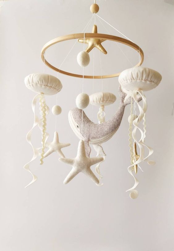 a neutral ocean-themed mobile with starfish, jellyfish, pompoms and a whale is a cool idea for a seaside or coastal nursery