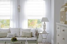 a neutral vintage room with white Roman shades and white semi sheer curtains is a very chic and stylish space that wows