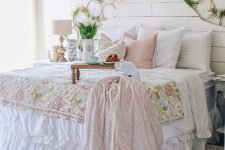 a pastel shabby chic bedroom with a white beadboard bed, pastel and floral bedding, lots of hoops with blooms, a bead chandelier