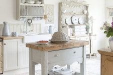 a romantic neutral shabby chic kitchen with beadboard cabinets, an off-white kitchen island and refined open storage units