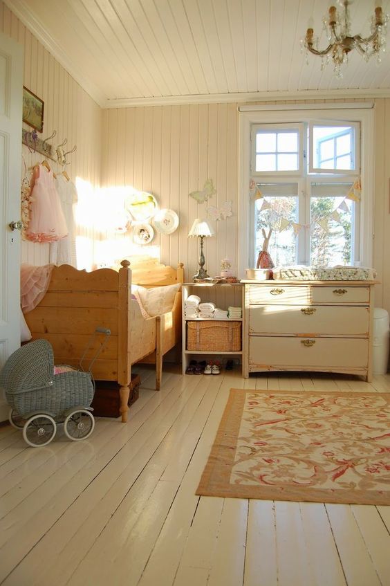 a rustic shabby chic kids' bedroom with vintage furniture, a crystal chandelier, a floral rug and baskets plus decorative plates