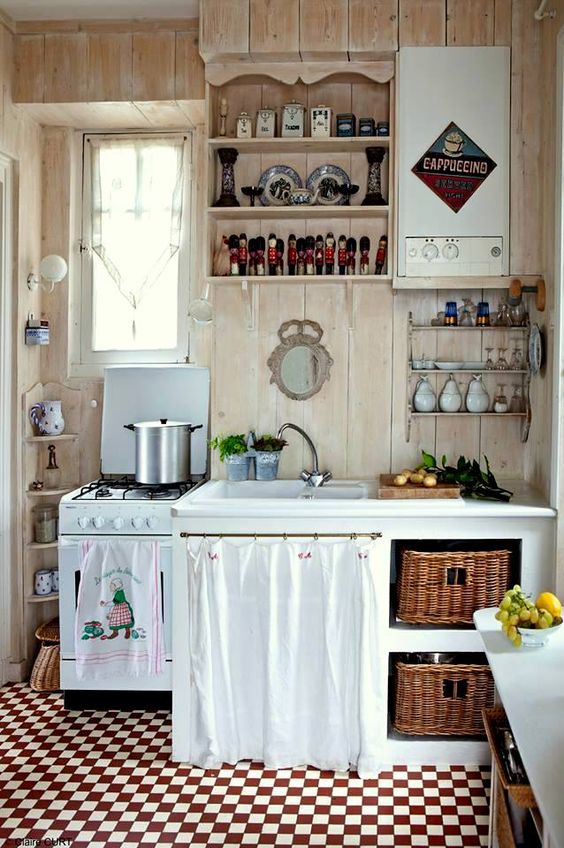 a rustic shabby chic kitchen in neutrals, with a white cabinet with baskets, a curtain over a cabinet, open storage units and vintage linens
