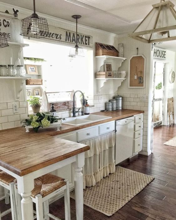 a rustic shabby chic kitchen with a ruffled curtain on a cabinet, metal and wooden pendant lamps and green blooms