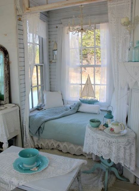 a shabby chic bedroom in white and pastel blue, with a bed in an alcove, with pastel blue bedding and lace and a vintage chandelier
