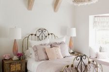 a shabby chic bedroom with a shabby forged bed, stained wooden furniture, a fluffy pendant lamp and pastel bedding