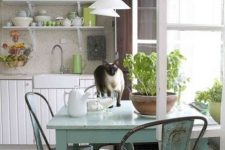a simple shabby chic kitchen with white beadboard cabinets, light blue shabby furniture, green touches and potted greenery