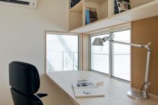 a stylish and cool minimalist home office with an open shelving unit, a desk, a black chair and small windows with a view