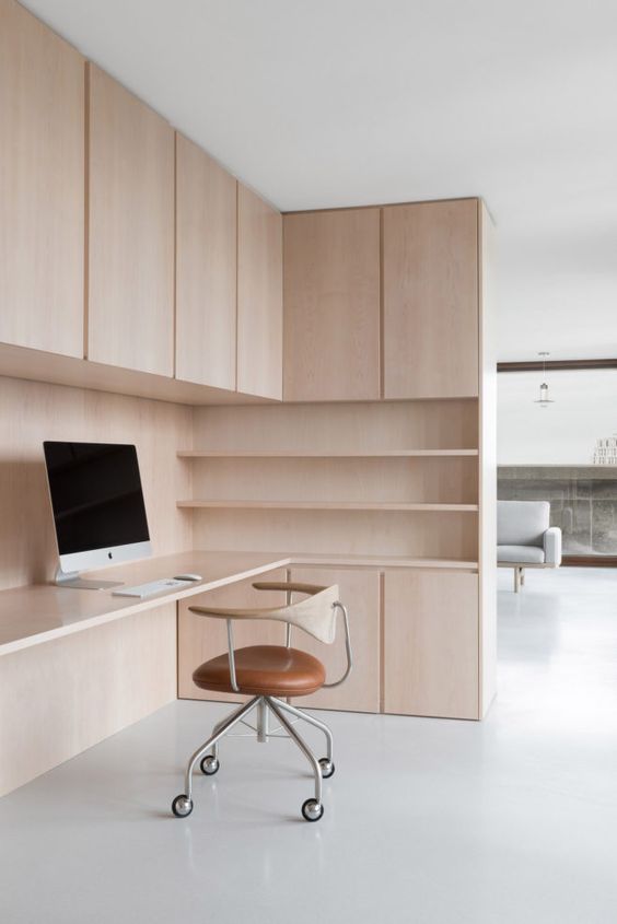 a stylish minimalist home office with light stained plywood, with storage units and open shelves, a cool plywood and leather chair