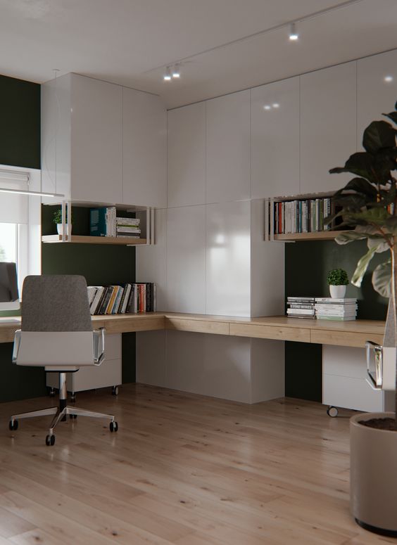 A very stylish minimalist home office with sleek white cabinets and a built in stained desk, a chair and potted plants