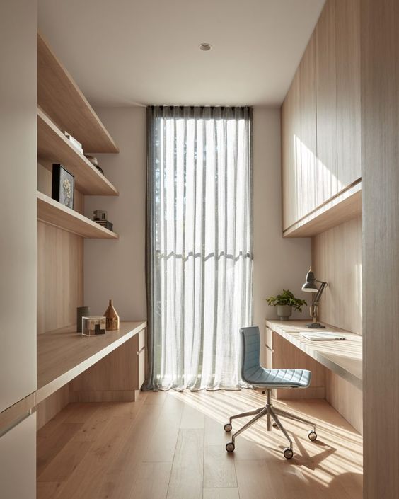 a welcoming minimalist home office with a built-in slek storage unit, open shelves, built-in desks and a blue chair plus a curtain