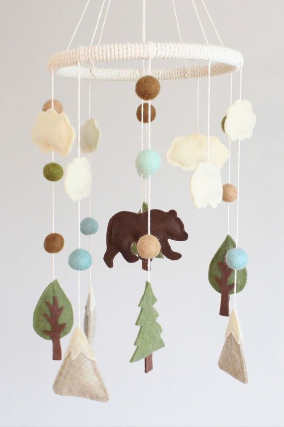 a woodland mobile with mountains, pompoms, clouds, trees and a bear is a cool and stylish solution made of felt