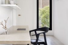 an airy minimalist home office with open shelves, a floating desk, a black chair and a narrow window for a view