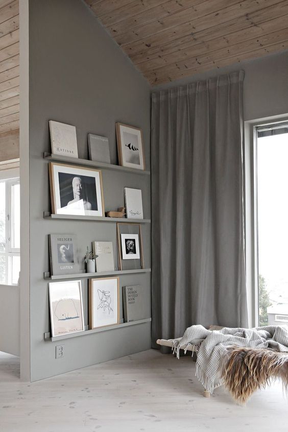 grey ledges match the grey wall and show off books and artworks beautifully and seamlessly looking chic
