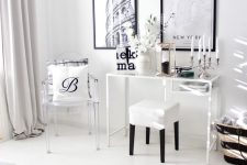 a Scandinavian room with a white Vittsjo desk, a white stool and a clear chair, a black and white gallery wall, a black candle and blooming branches