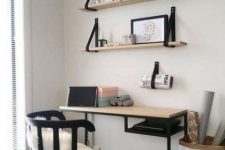 a Scandinavian working space with open shelves and a Vitssjo desk with a wooden countertop, a black chair and some art and books