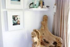 a beautiful driftwood chair, some ocean-inspired artworks and a shelf with corals create a sea-inspired nook here