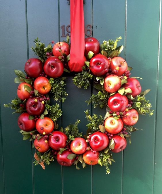 A bright fall wreath of bold apples, greenery, berries and a red ribbon for accenting your front door and make it fall like