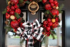 a bright fall wreath of faux fruit, berries, pinecones, evergreens and a large plaid bow on top