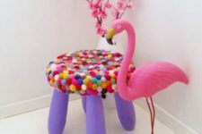 a bright purple IKEA Mammut stool covered with bright pompoms is soft and cute and very colorful
