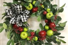 a bright wreath of foliage, green and red apples and a plaid bow is a cool decoration in farmhouse style