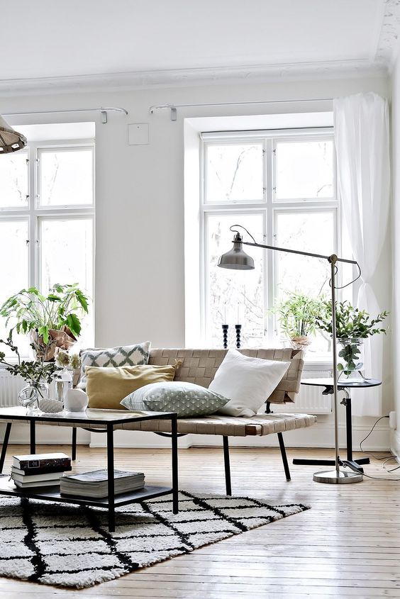 a catchy Nordic space with a leather bench, a table, an IKEA Ranarp floor lamp and greenery around
