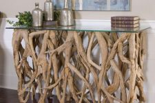 a chic console table of lots of driftwood and a glass tabletop is a refined and cool idea for a beachy or eco-friendly interior