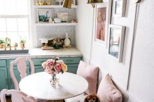 a cute small nook with a neutral bench, pink chairs and pillows, a round table and a lovely bright gallery wlal