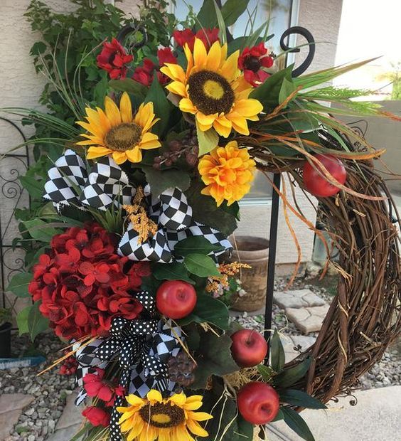 a fun fall wreath of vine, faux blooms, apples, grasses and leaves and some printed black and white bows and ribbons