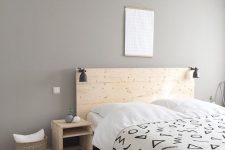 a laconic minimalist bedroom with light-colored wooden furniture, a basket, artworks and black IKEA Ranarp sconces