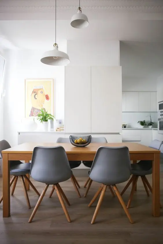 a minimalist dining space with a wooden table, grey chairs, white IKEA Ranarp pendant lamps is very cozy