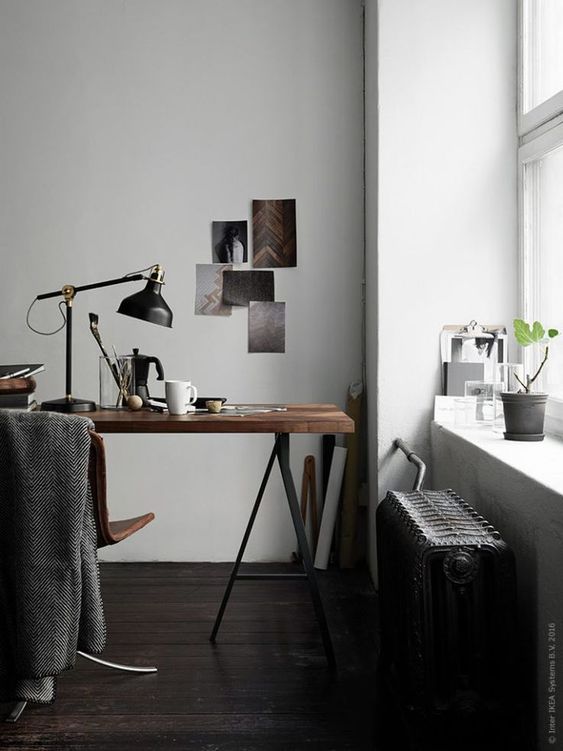 a moody home office nook with a trestle desk, a leather chair, a black radiator and a black IKEA Ranarp table lamp