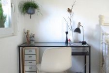 a small working space by the window with a black Vittsjo desk, a white chair, a small fire cabinet under the desk, a black clock and greenery