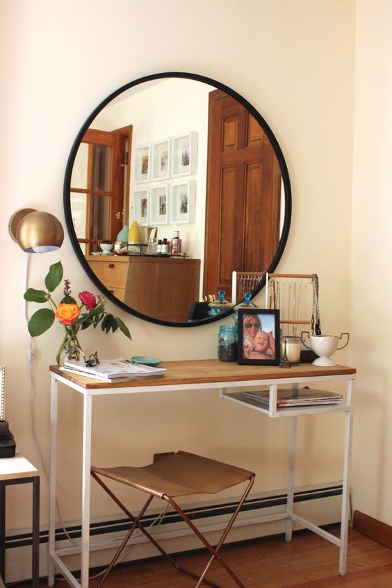 A stylish conole table of an IKEA Vittsjo desk, with a wooden tabletop to make it more rustic like, with accessories, decor, candles and a round mirror in a black frame