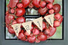 a super bold fall wreath of faux red apples, hay, a burlap banner and a plaid ribbon is cool for decorating your front door
