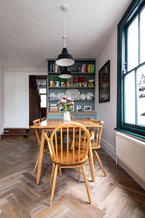 a vintage dining space with a wooden dining set, a blue storage unit and black pendant IKEA Ranarp lamps