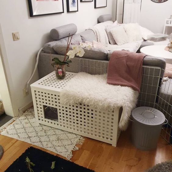 a white IKEA Hol side table with a pet retreat inside and a faux fur cover is a double-function item