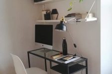 an elegant Scandinavian working nook with open shelves, a black Vittsjo desk, a white chair, a basket for storage, a clock and some greenery