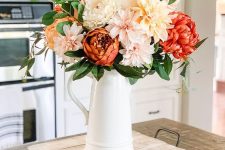 a bold and fun fall faux flower arrangement of neutral, blush and red blooms and greenery is very elegant
