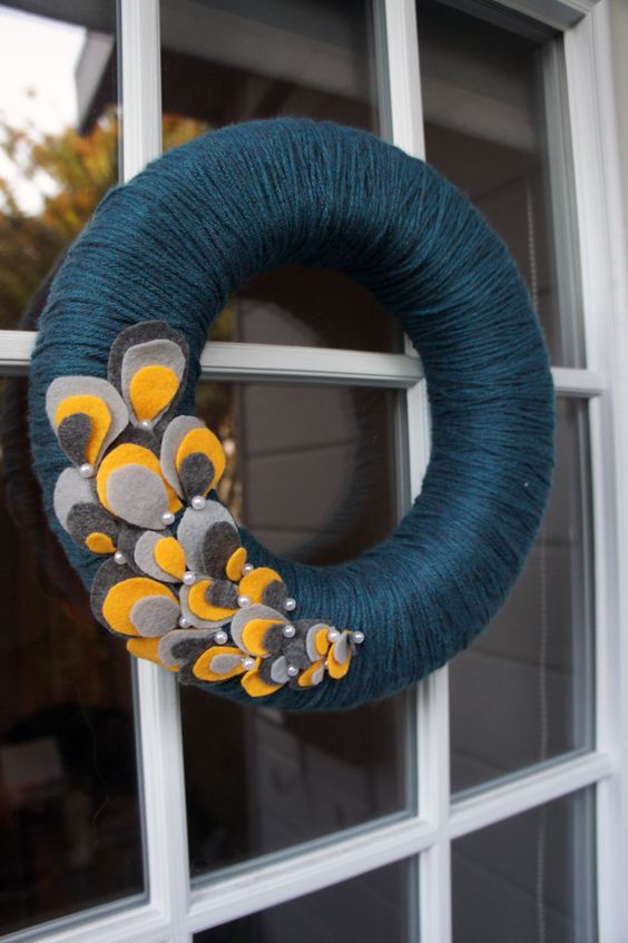 A bold fall wreath styled in non typical colors, covered with navy yarn and with colroful fabric petals and pearls