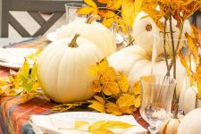a bright and natural fall centerpiece of white pumpkins and bright yellow leaves on branches is amazing