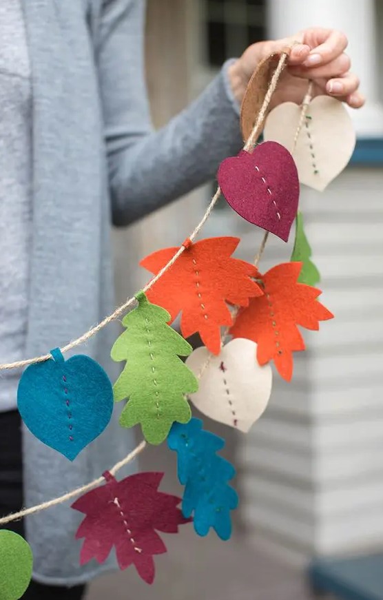 a bright fall banner of bold fall leaves cut out of felt is a fun and cool idea that can be easly made by you yourself