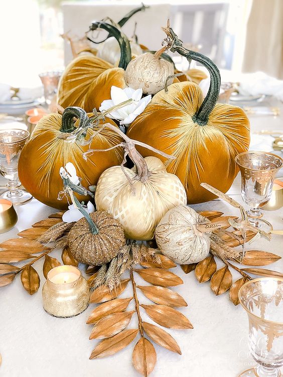 a bright fall centerpiece of mustard velvet pumpkins and glam printed ones, gilded leaves and candles is lovely and refined