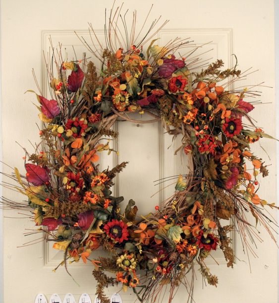 a bright fall twig wreath with lots of bold faux leaves, blooms, berries and fruits is a statement decoration