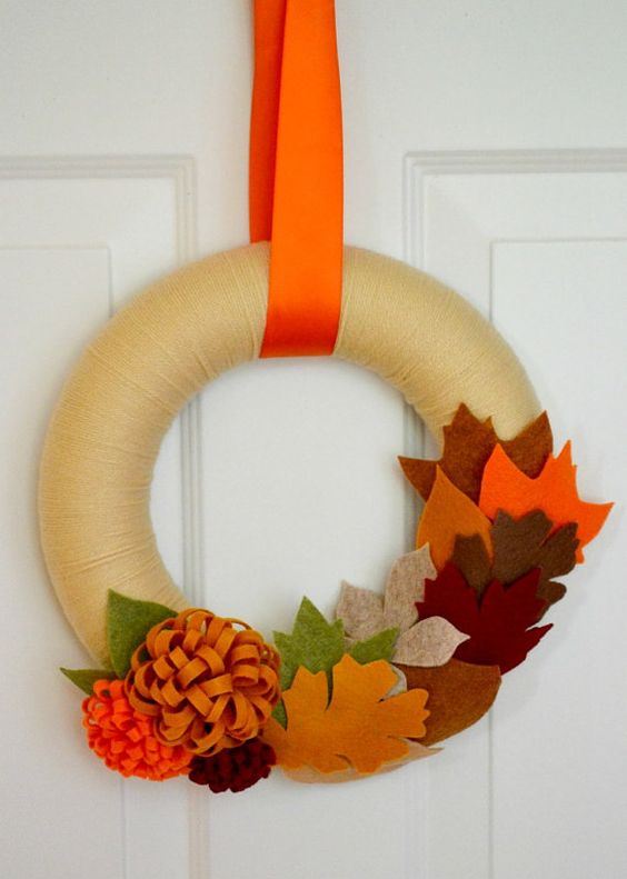 a bright fall wreath covered with neutral yarn, colorful fabric leaves and flowers is easy to make yourself