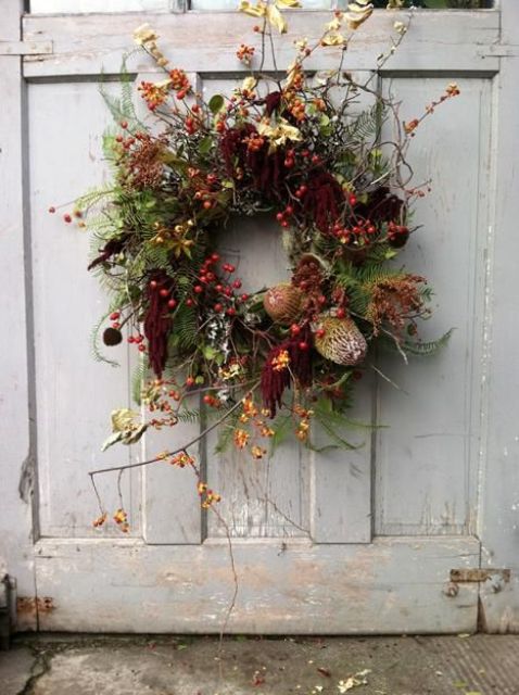 a bright fall wreath with twigs, berries, dark blooms, fabric ribbons and dried flowers is very refined
