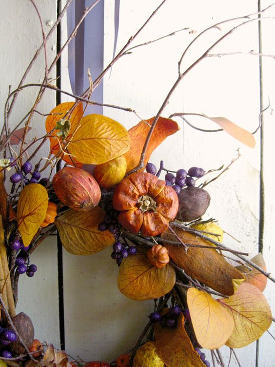 A bright fall wreath with twigs, berries, faux veggies and fruits, bright leaves is a harvest inspired piece