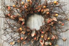 a brigth natural fall wreath with twigs, acorns, berries, pinecones is lovely way to add a woodland feel to the space