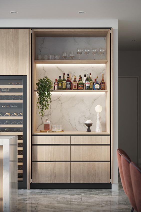 A built in minimalist mini bar in the kitchen, with a marble backsplash, built in shelves with lights and sleek drawers
