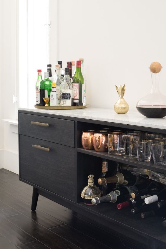 a chic black home bar with open and closed storage compartments, gold touches and a gold tray is elegant