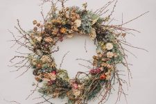 a chic twig fall wreath with moss, berries, twigs, dried leaves and blooms plus pinecones for a fall feel
